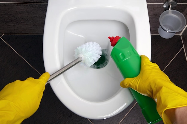 Cleaning and disinfecting the toilet in yellow rubber gloves