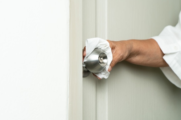 Cleaning door knob with alcohol spray for Covid-19 Coronavirus prevention