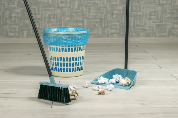 Cleaning of garbage in the room with a dustpan and a brush with a handle