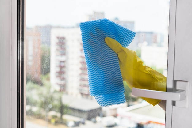 Cleaning glass of home window by blue rag