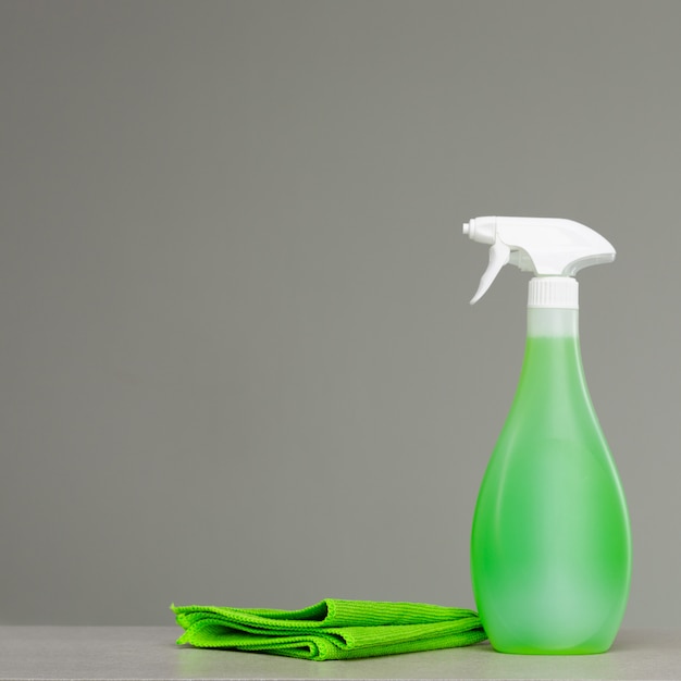 Cleaning green spray bottle with plastic dispenser and cloth.