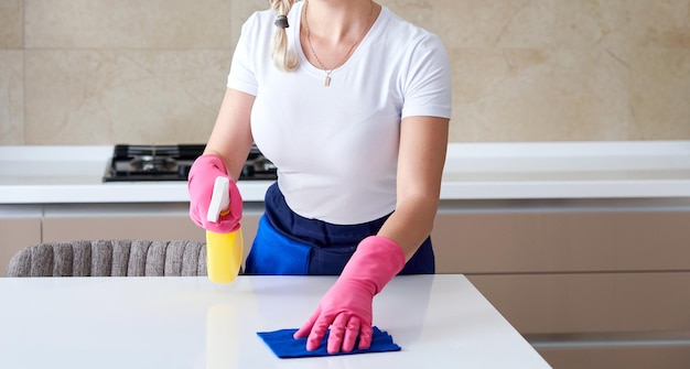 Cleaning home table sanitizing kitchen table surface with disinfectant spray bottle washing surfaces with towel and gloves COVID19 prevention sanitizing inside