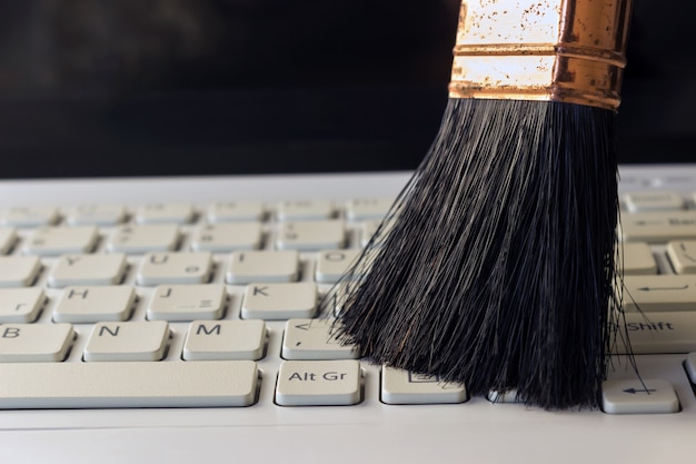 Cleaning keyboard from dust by black brush.