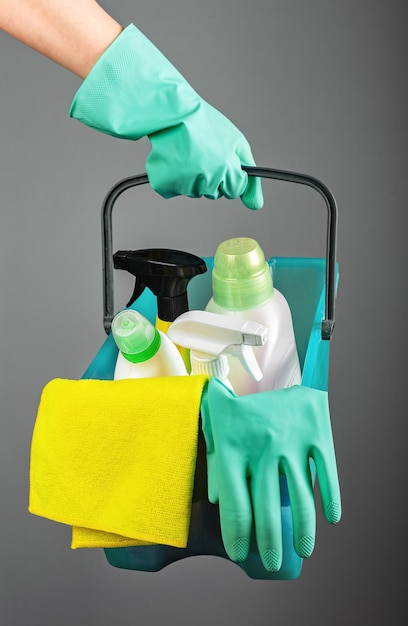 Cleaning kit in basket Cleaners hand holding cloths detergents bottles