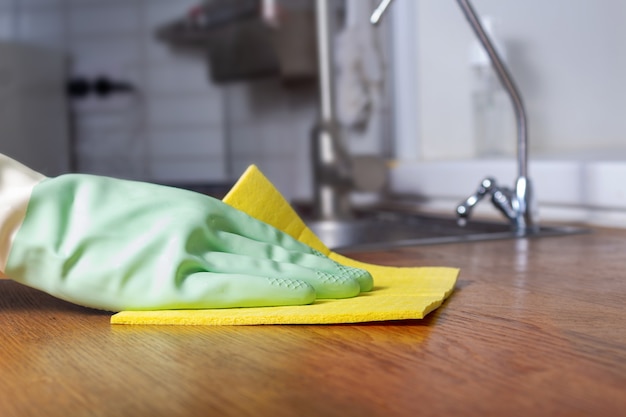 Cleaning kitchen with green rubber glove closeup