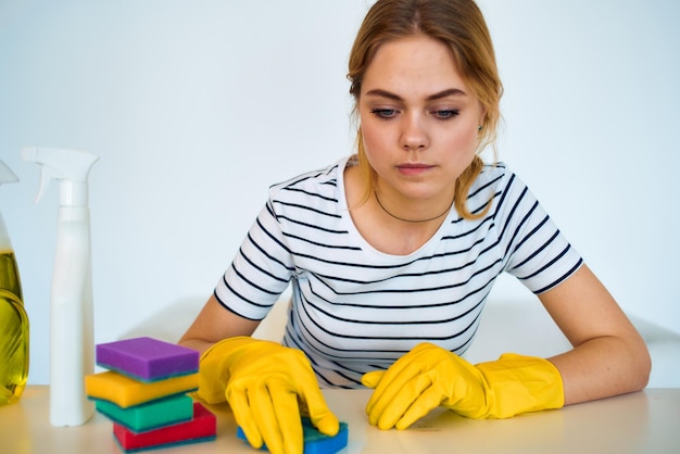 Cleaning lady sitting at the table with detergent sponge rubber gloves housework rendering services