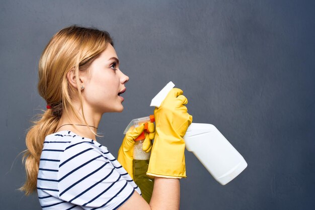 Cleaning lady in striped tshirt rubber gloves cropped gray background