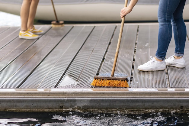 Cleaning Pier on Lake or Sea Beach Pier Service Yacht Boat concept Washing Pier floor with Brush