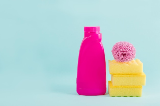 Cleaning pink supplies collection on blue background Housework concept Pink bottle with detergent