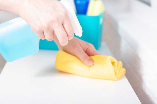 Cleaning service with blue spray and wipe. Woman using detergent and disinfectants