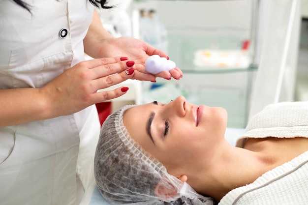 Cleaning the skin with foam, a beautiful woman in the beauty salon beauty. Cosmetologist job.