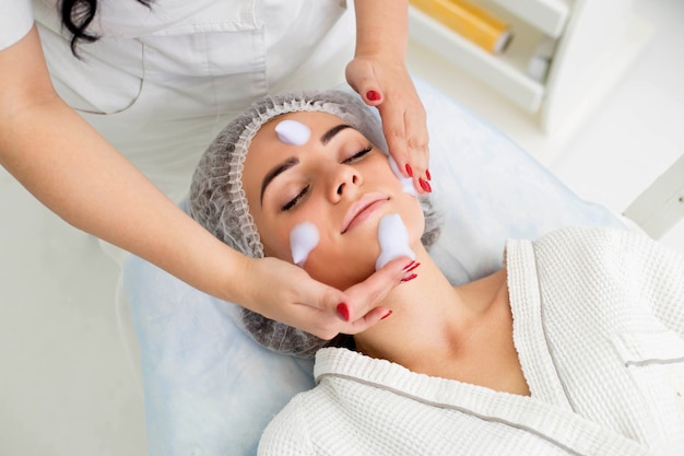 Cleaning the skin with foam, a beautiful woman in the beauty salon beauty. Cosmetologist job.