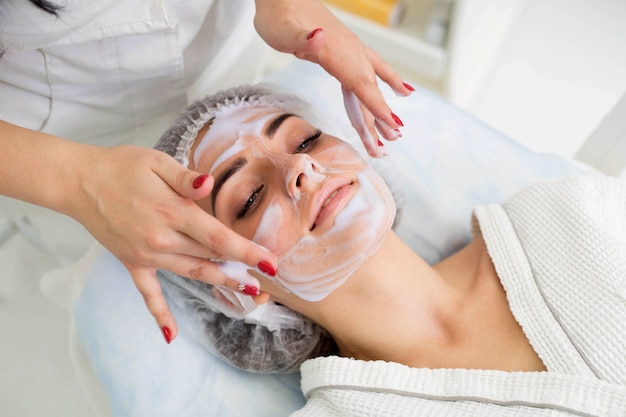 Cleaning the skin with foam, a beautiful woman in the beauty salon beauty. Cosmetologist job.