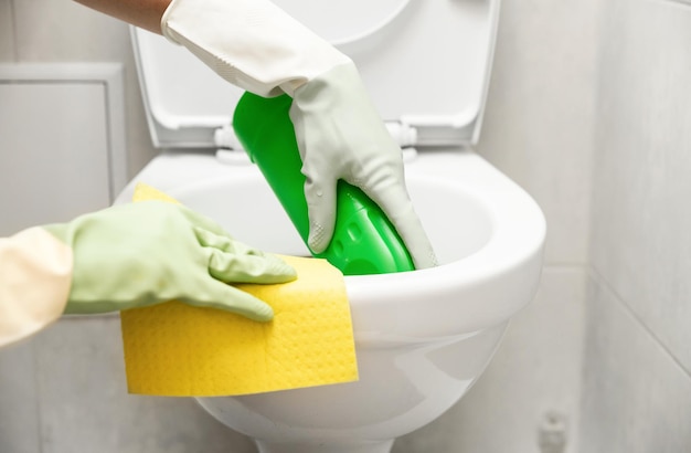 Cleaning the toilet closeup hands holding a rag and detergent for cleaning