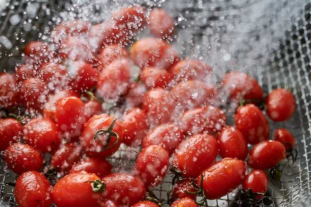 Cleaning the vivid red ripe tomatoes in the metal wire basket