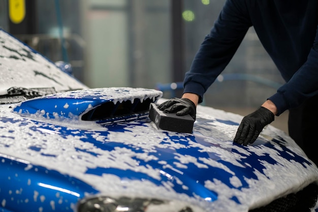 Cleaning and washing a car wiping the body with foam and sponge