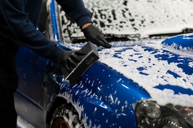 Cleaning and washing a car wiping the body with foam and sponge