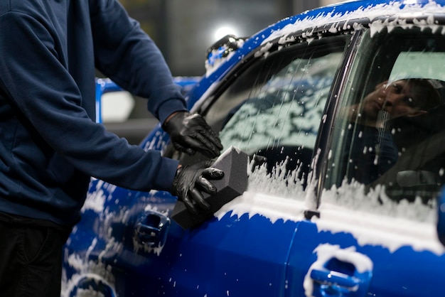 Cleaning and washing a car wiping the body with foam and sponge