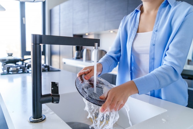 Cleaning woman housewife wash up dishes after dinner in the modern kitchen