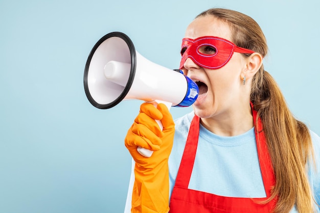 Cleaning woman in red hero mask with megaphone on blue background