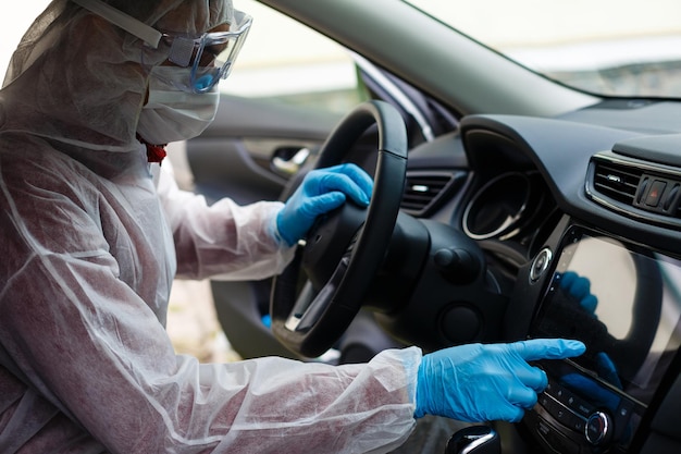 Cleansing car interior and spraying with disinfection liquid. Hands in rubber protective glove disinfecting vihicle inside for protection from virus disease