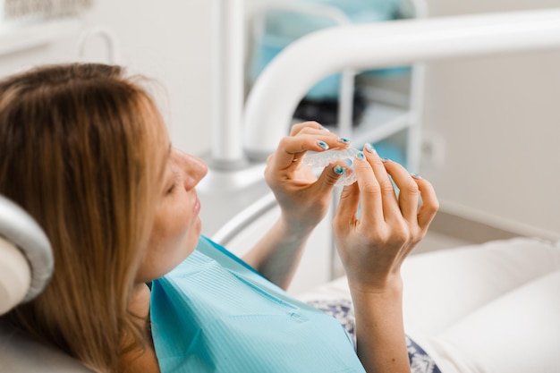 Clear aligner for bite correction and shape of teeth Orthodontist shows transparent removable retainer for patient woman in dentistry