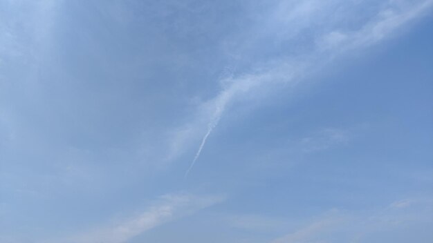 A clear blue sky with a jet trail in the sky.