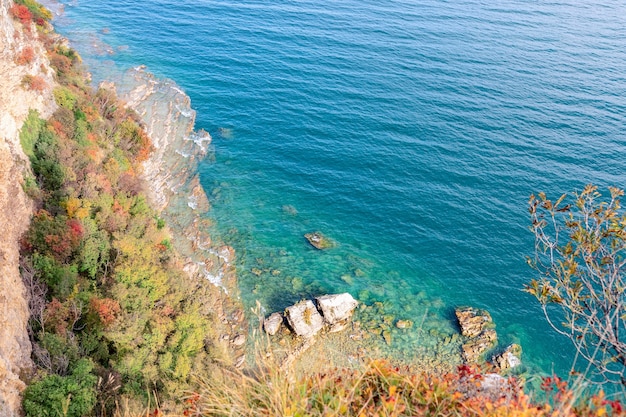 The clear emerald waters of Lake Garda and rocky shore in the fall period