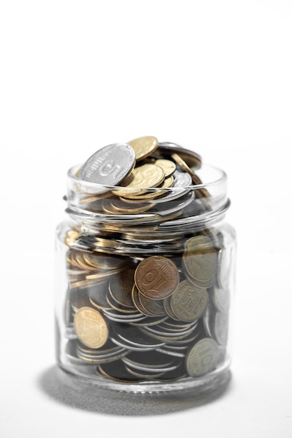 Clear glass jar for tips with coins money isolated on white Finance concept