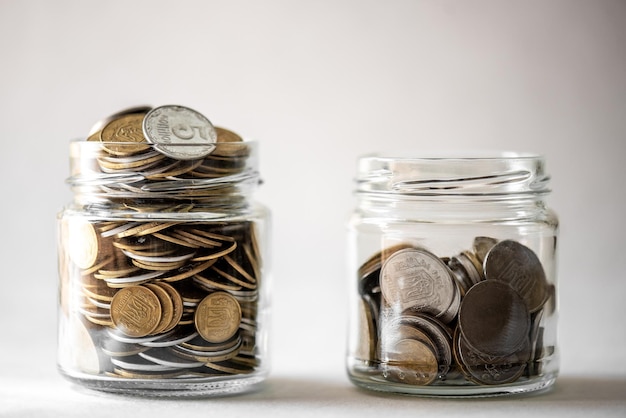 Clear glass jar for tips with coins money isolated on white Finance concept