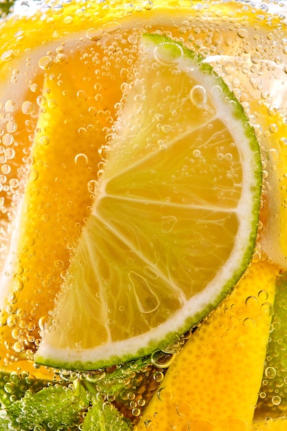 In a clear glass mint leaf slices of lime and lemon with bubbles macro photo of summer drink mojito