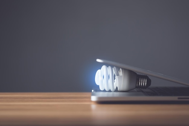 Clear light bulb with modern laptop on the office desk with grey space wall background Use for the idea of future creative innovation Learning Education or working