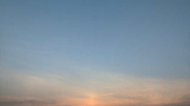 A clear sky with a blue sky and the sun is setting in the background.