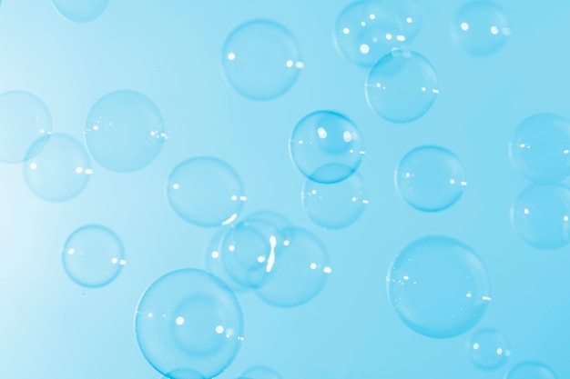 Clear transparent soap bubbles floating on blue background.