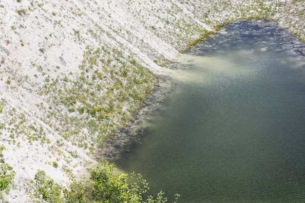 Clear water in a chalk quarry with a steep bank overgrown with grass and bushes