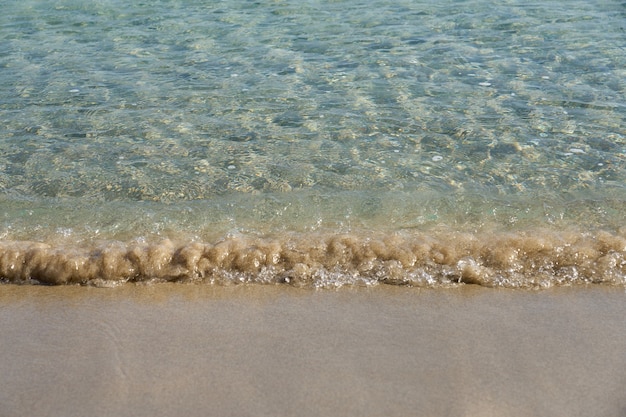 Clear waves and colorful sand on tropical sandy beach in Crete Greece.