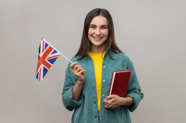 Clever cheerful woman holding in hands book and british flag education courses abroad