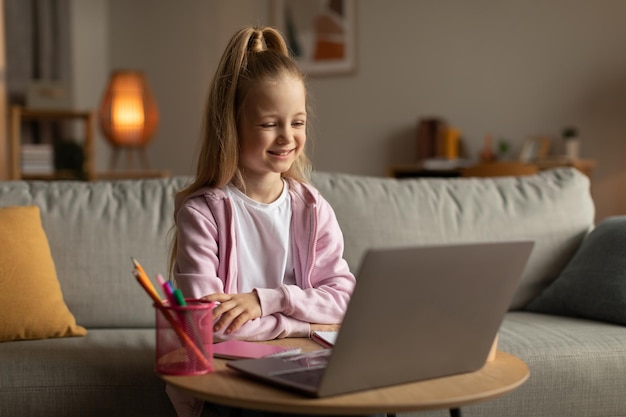 Photo clever schoolgirl learning online using laptop computer sitting at home