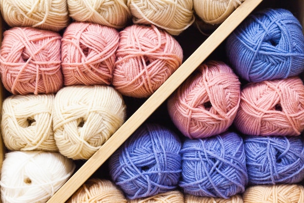 Clews of threads for knitting of different colors are stacked on the shelves closeup