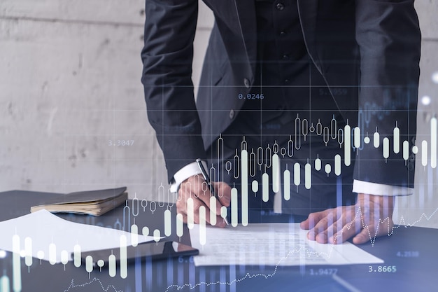 A client in formal wear is signing the contract to invest money in stock market Internet trading and wealth management concept Forex and financial hologram chart over the desk