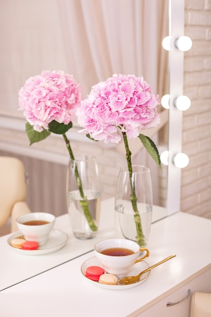 Client place in hairdressing beauty salon with cup of tea macaroons and flower