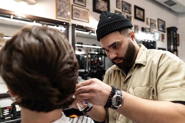 The client receives a haircut in a barbershop. Men's Hair Care. Haircut with scissors