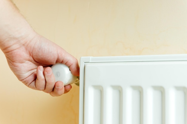 Climate optimism and climate control a man switches the temperature on the batteries saves heat prot