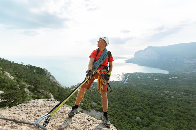 Climber climbs the mountain on a cable with a view of the forest and the sea