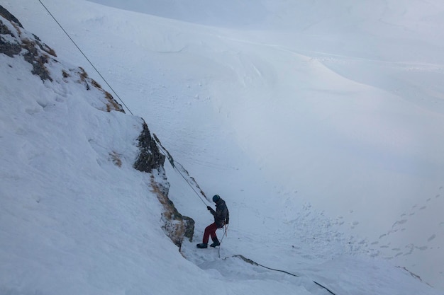 A climber in a helmet descends on a rope down the cliff