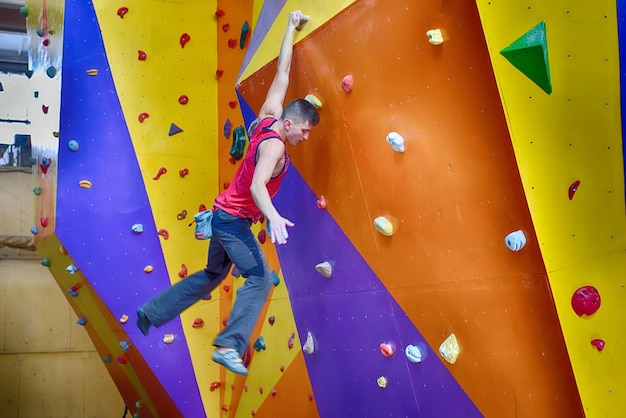 Climber man climbing on color practice wall