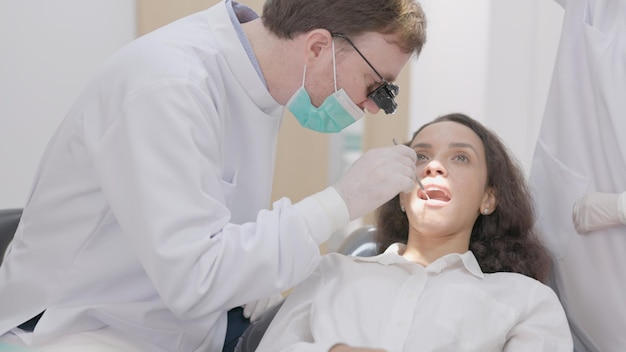 In the clinic a dentist cleans the teeth of a patient