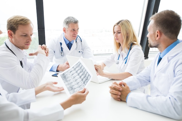 Clinic, people, healthcare and medicine concept - group of medics with brain x-ray scan at hospital