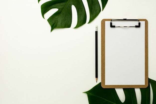 Clipboard and white paper on white office desk background. Flat lay design.