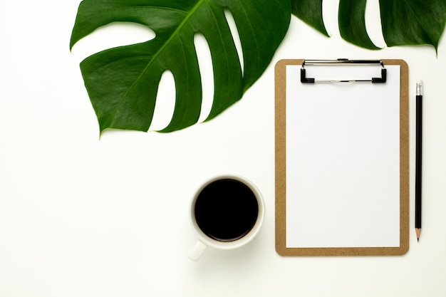 Clipboard and white paper on white office desk background. Flat lay design.